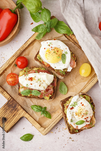 Wooden board of tasty sandwiches with egg on light background