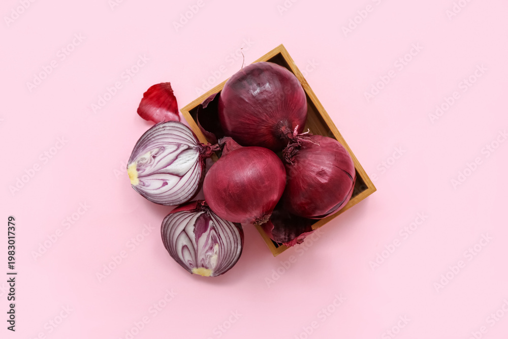 Obraz premium Wooden box with fresh red onions on pink background