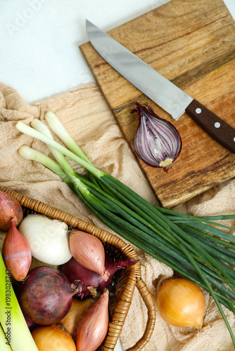 Wicker basket with different kinds of onion on light background