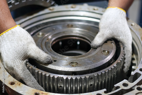 Foto Mechanic hands installing a heavy planetary gear carrier into an automatic transmission housing during a professional gearbox rebuild and maintenance service