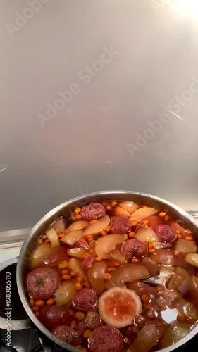 compote is cooked in a saucepan on the stove, apple-strawberry compote in a silver saucepan, opening and closing the lid.  selective focus