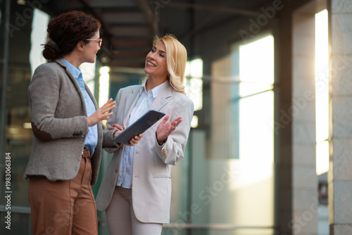 Business women discussing project using digital tablet outdoors