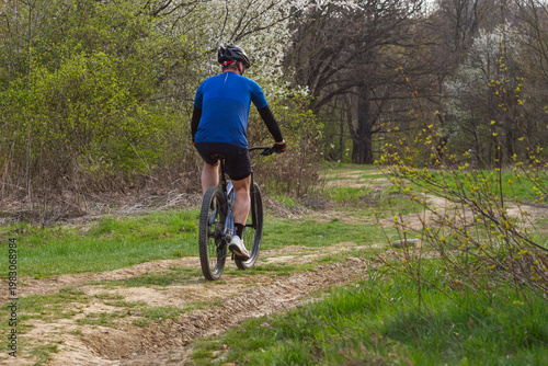 Mountain Biker Riding Off-Road Trail Through Spring Forest Landscape | Rowerzysta MTB jadący szlakiem terenowym na tle wiosennego leśnego krajobrazu