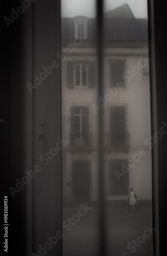 Blurred, suggestive and romantic scenery street  through net curtains of one lady walking in an european street