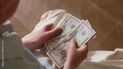 Child counting dollar bills, young kid learning to manage money and savings, financial literacy education concept indoors, hands close-up