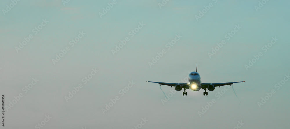 Fototapeta premium Front side view commercial passenger aircraft or cargo transportation airplane flying on blue sky over sea and spread the wheel prepare landing to airport in cloudy sunset evening sky