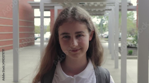 Portrait Friendly Girl With Backpack Standing Outside School Building. School Girl Looks at Camera. Schoolgirl in Uniform With Backpack Near an Middle School Building. Child Education Learning.