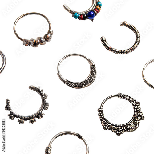Pattern of varied silver nose rings with ornate details, against a black background