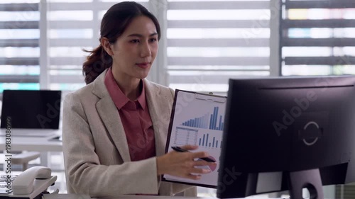 Asian adult woman professional presenting business data report analytics during online video conference meeting in modern office work remotely communication technology