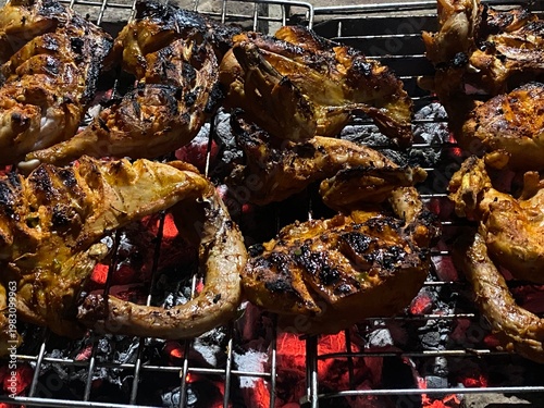 Grilled chicken skewers sizzling on barbecue grill with flames and coals outdoor cooking and food preparation