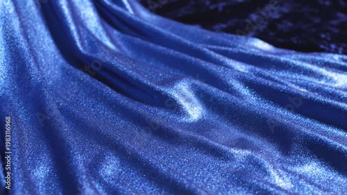 Close-up shot of a shiny, textured blue fabric with elegant folds and highlights.