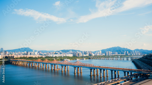 High angle view of curved highway traffic in Seoul Forest area with modern skyscrapers and park.