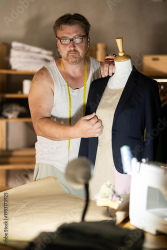 Cuadro en lienzo Middle-aged male dressmaker fitting jacket on mannequin
