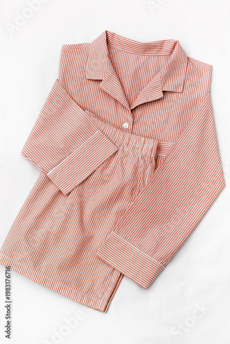 Pink striped Pajama on white sheet background. Top view home sleepwear female from soft cotton red colored on bedclothes. Cozy pyjamas of shirt and shorts for comfort rest, flat lay, pastel colored