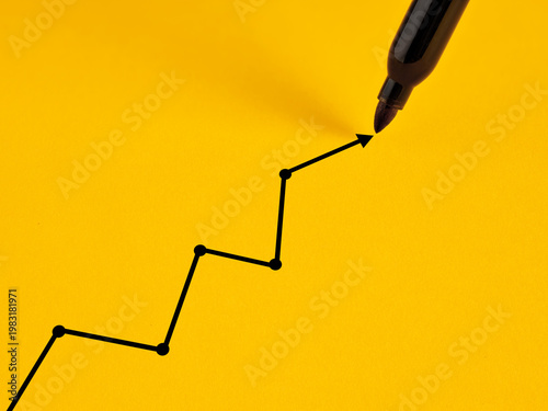 Marker drawing growing line graph on yellow background