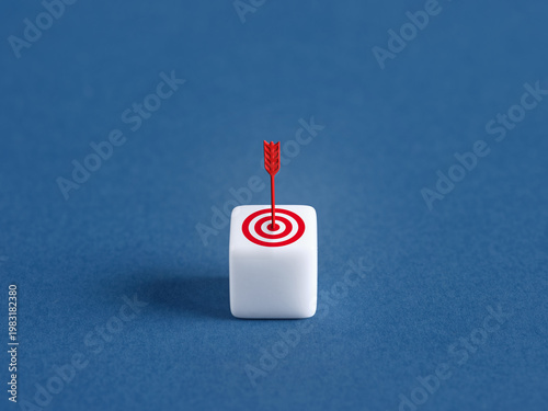 Arrow hitting bullseye target on white block