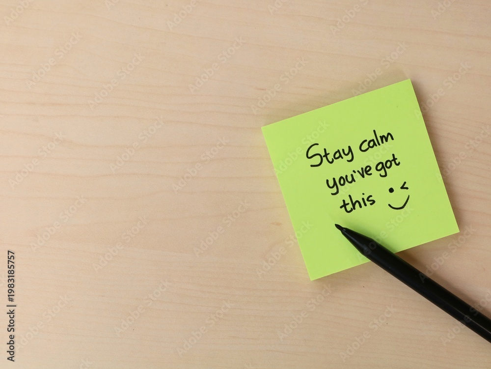 Obraz premium Stay calm you’ve got this message on green sticky note on wooden desk. Concept for mental health, workplace productivity, exam preparation, and positive mindset