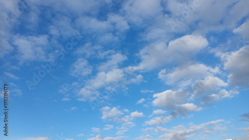 Vászonkép White fluffy clouds scattered across a bright blue daytime sky