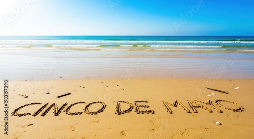 A festive beach scene with the words 'Cinco de Mayo' written in the sand on a sunny day with a clear