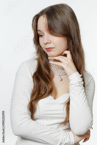 Portrait of a pensive young girl wearing pearl jewelry.