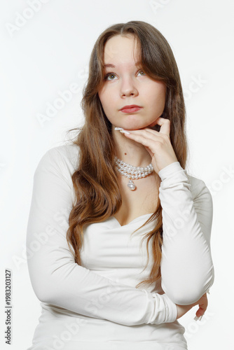 Portrait of a pensive young girl wearing pearl jewelry.