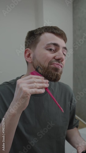 White man brushing dye through beard strands with measured strokes, saturating roots to tips, steady hand and mirror check