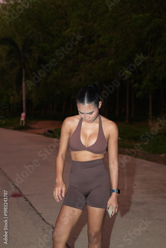 Bilde på lerret Fit Thai Woman in Brown Halter Sportswear Looking Down Outdoor Night Fitness Con