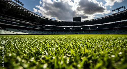 Close up low angle view of green grass on a football soccer stadium pitch with blurred background stands under a cloudy sky with soccer field with ground level