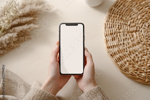 Hands holding a modern smartphone with a blank screen, neutral tones, soft textures