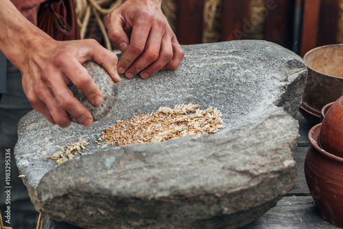 Photos Human hand rotating an ancient stone grinding machine for smashing grains
