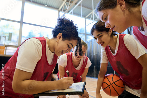 Female basketball players discussing game strategy with coach
