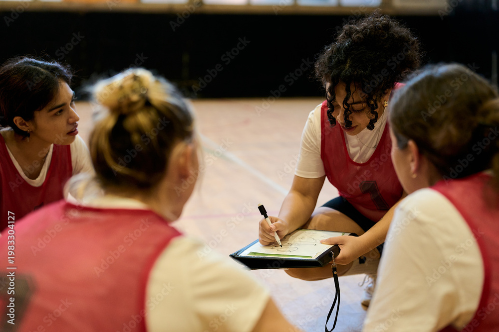 Fototapeta premium Coach explaining strategy to female basketball players