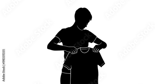 Silhouette of a young person holding up a t-shirt, preparing to fold or inspect it.