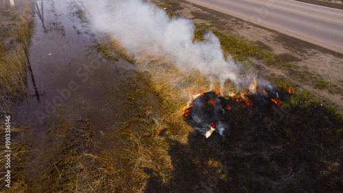 Фотография A high-angle drone shot capturing a controlled burn or accidental fire of dry gr