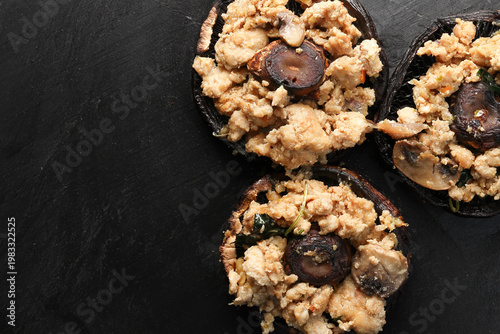 Stuffed roasted fried large portobello mushroom minced chicken on black slate background closeup details