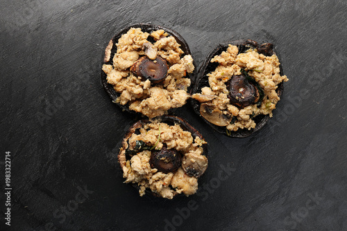 Stuffed roasted fried large portobello mushroom minced chicken on black slate background closeup details