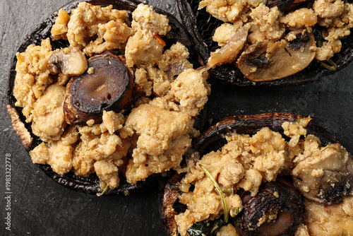 Stuffed roasted fried large portobello mushroom minced chicken on black slate background closeup details
