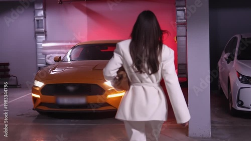 Stylish young woman unlocking yellow sport car with key fob in underground parking, car lights flashing. Perfect for automotive, lifestyle and urban nightlife themed commercial projects.