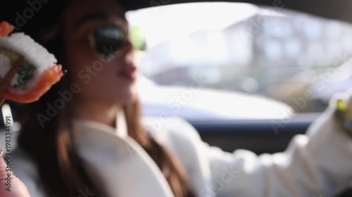 Close-up of young woman picking sushi with wooden chopsticks from box while sitting in car. Perfect for food, lifestyle, urban, eating on the go and modern life themed projects