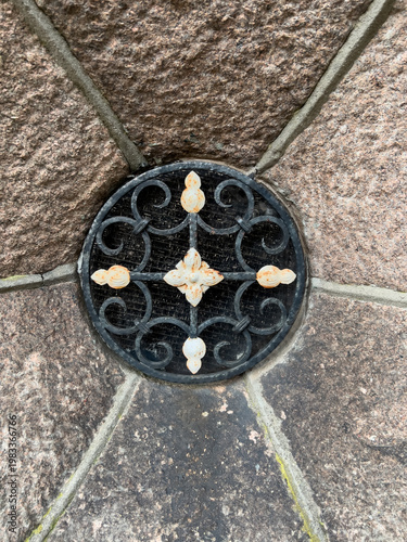 Kleines Metall Gitter in einer alten Mauer aus rauem braunen Stein