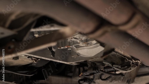Oil dripping from underneath a car that's being repaired on a car lift.