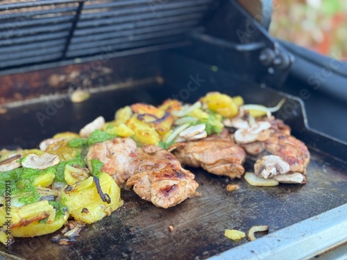 Photography Close-up shot of grilled chicken, potatoes, mushrooms and vegetables on a griddl