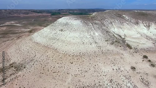 Aerial view of eroded limestone mountains and white sandstone slopes in barren arid desert terrain. Treeless landscape, topography, wilderness, highlands depict rugged regional geology natural.