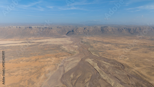 Aerial Desert Valley with Dry Riverbed and Mesa Cliffs