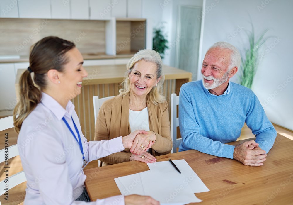 Obraz premium Happy senior old family couple clients make financial insurance estate business deal contract signing and shaking hands, agent lawyer, satisfied mature customers signing contract meeting bank manager 