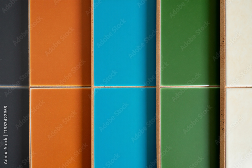 Fototapeta premium Close-up of colorful glazed ceramic tiles arranged in grid, vibrant orange, bright blue, deep green and neutral beige squares, textured grout lines, contemporary design