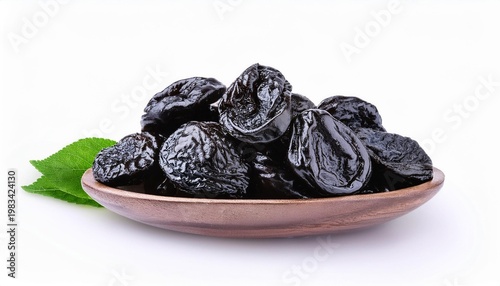 Prunes in wooden bowl with leaves