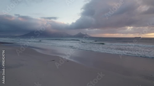 Aerial Drone Shot of Bloubergstrand Beach at Sunset, Panoramic View Across Table Bay toward Table Mountain and Cape Town City Skyline with Blue Moody Clouds
