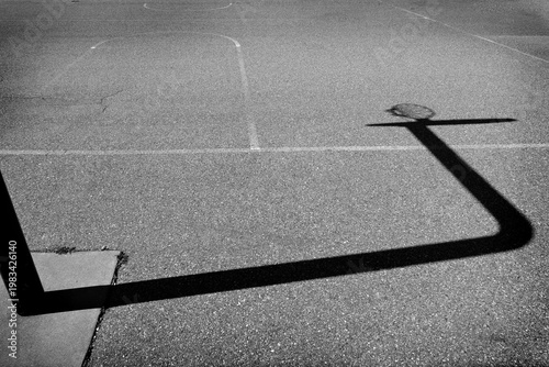 Silhouette of a Basket Ball Hoop in Urban Inner City Park with Painted Lines for Basket Ball Court on Asphalt