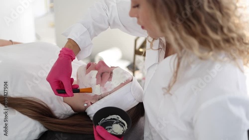 Skincare specialist distributes the clay mask thoroughly over the client's face, ensuring even coverage for a balanced complexion
